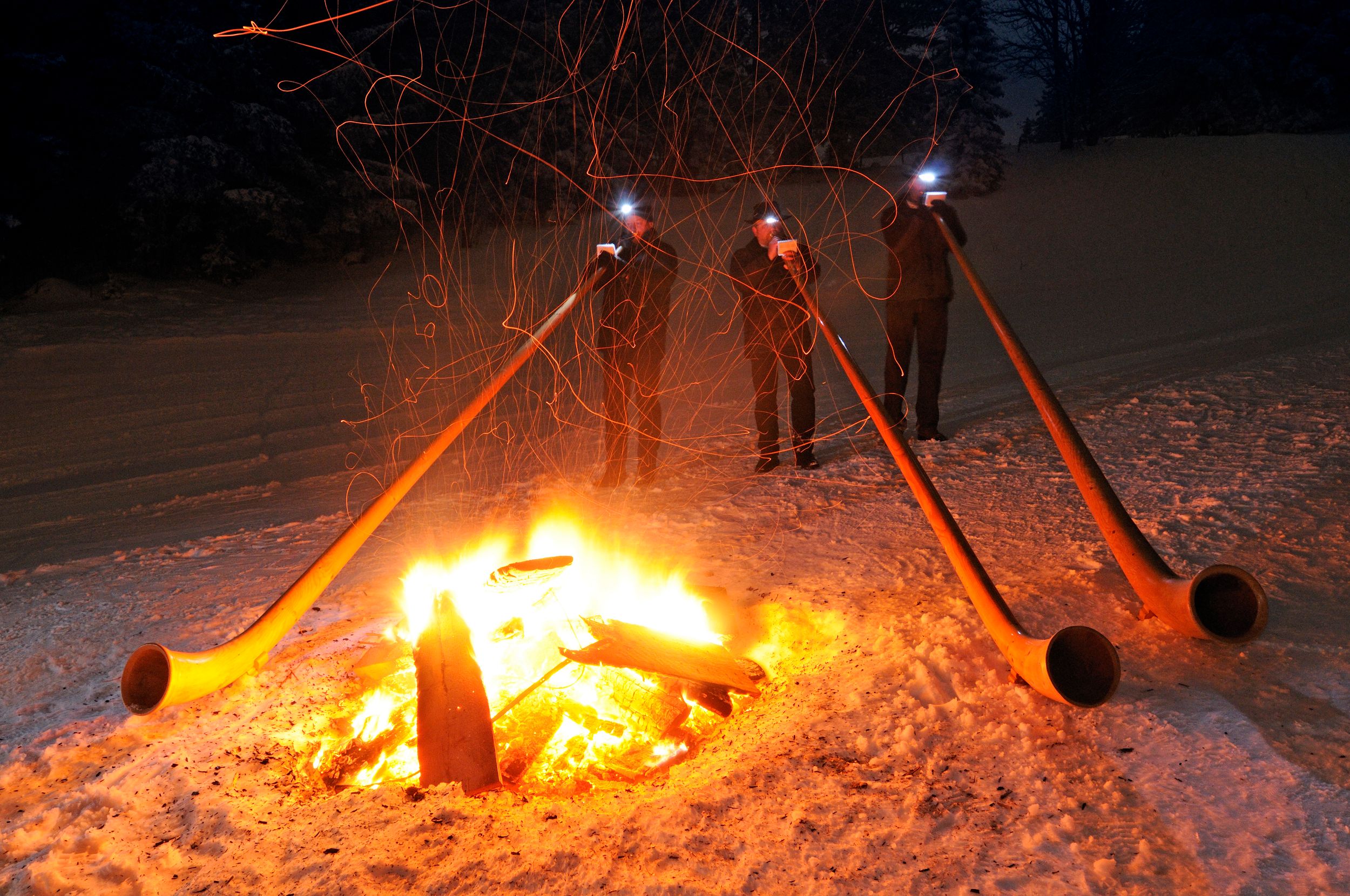 Alphornblaeser im Winter mit Lagerfeuer